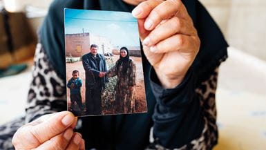Une femme du Moyen-Orient brandit une photo de son mari décédé, sur laquelle figure son fils.