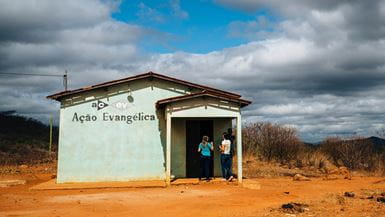 Dos mujeres jóvenes entran en una pequeña iglesia de cemento en una zona rural de Brasil.