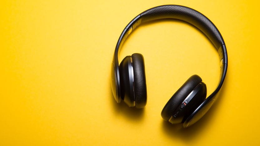 An image of black headphones on a yellow background