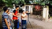 Dois homens e quatro mulheres de pé ao lado de um portão de metal, usando uma câmera como parte de um workshop de vídeo participativo em Mianmar