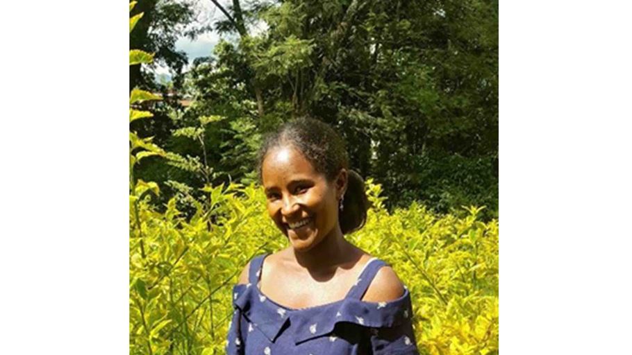Smiling woman standing outside In front of green bushes