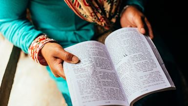 Une Népalaise vêtue d’une robe turquoise lit la Bible dans un atelier communautaire.
