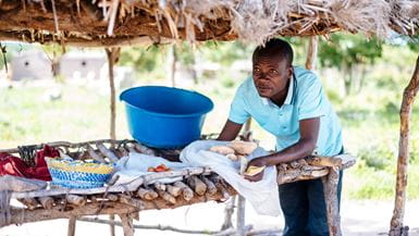 Un hombre vende frutas, verduras, granos y pan en el puesto de su familia
