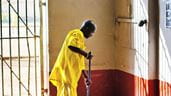 Dans sa salopette jaune, un homme incarcéré à la prison de Luzira, en Ouganda, nettoie le sol d’une cellule de prison.