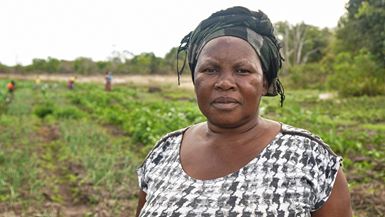 Woman in a field. She is part a community project that works to strengthen land rights of rural communities