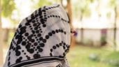 Uma sobrevivente da violência sexual e de gênero com um lenço estampado com bolinhas na cabeça, olhando para longe