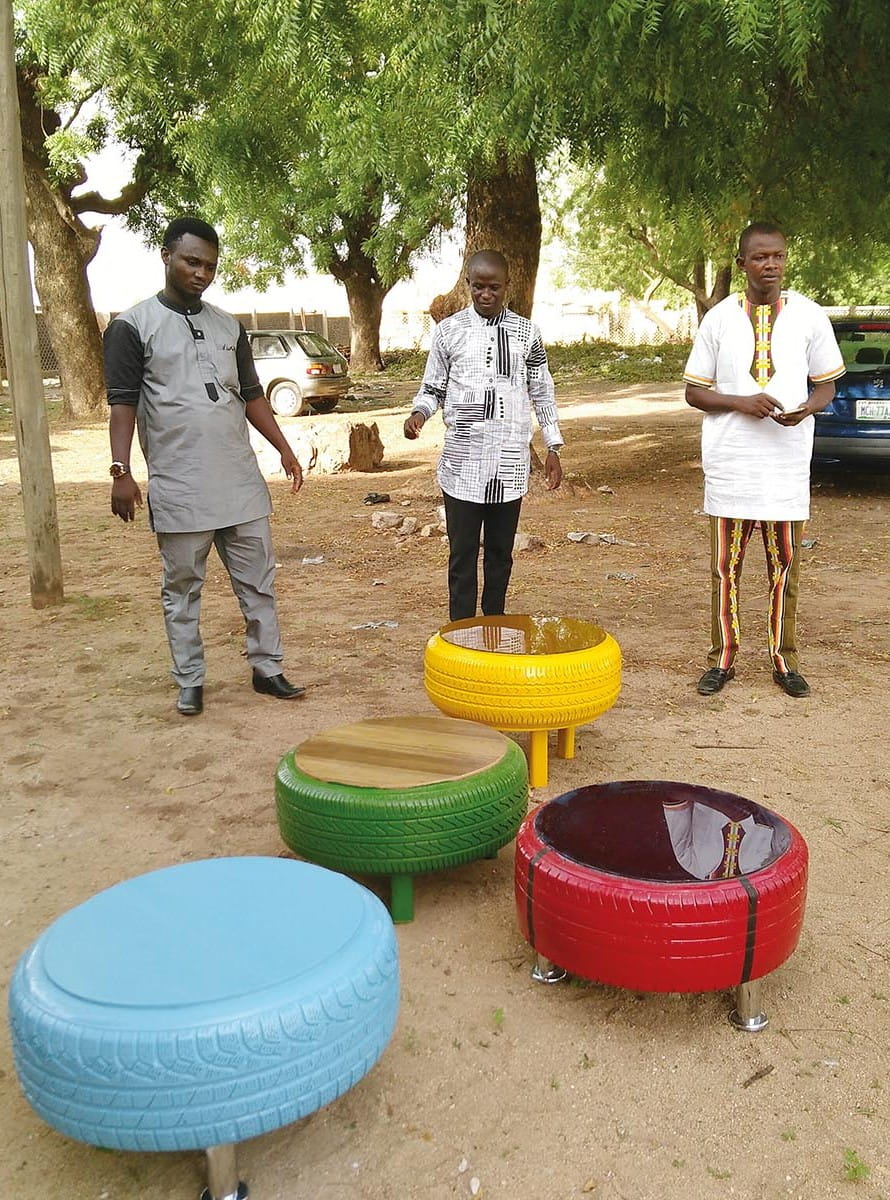 Jovens em Yola, na Nigéria, com mesas de centro feitas com pneus velhos. Foto: Naomi Foxwood/Tearfund