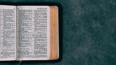 Pages de la Bible posée sur une surface en bois gris, ouvertes sur les psaumes 60 à 62.