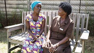 Duas mulheres treinadas em cuidados psiquiátricos sentadas lado a lado em um banco, no Zimbábue