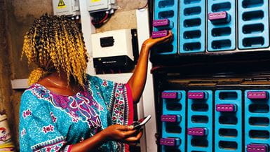 Uma senhora africana verificando as baterias “MOPO” em um centro de carregamento
