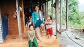 Une femme tient la main de ses deux jeunes enfants sur les marches de leur hutte dans le Népal rural.