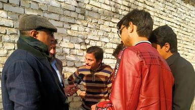 No Paquistão, um grupo de homens em pé em um círculo, com um deles falando no microfone