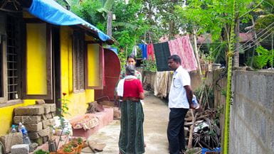 A woman and a man from a local organisation stand and listen to an older lady in Kerala, India