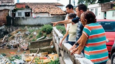 Quatre membres de la communauté se tiennent contre la rambarde d'un pont qui surplombe la rivière Tejipió, très polluée, à Recife, au Brésil
