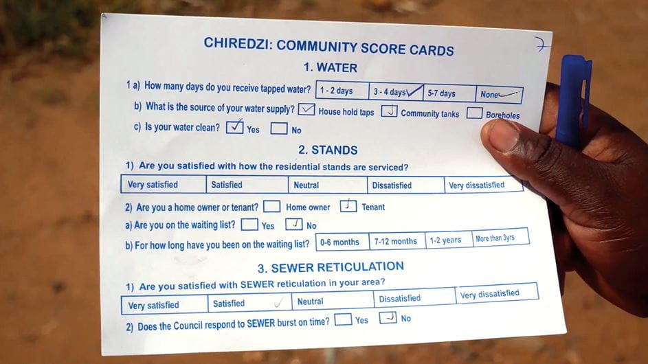 Uma mão segurando um formulário simples, utilizado para coletar informações sobre a qualidade dos serviços locais