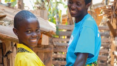Uma mãe no Burundi sorrindo para a filha, enquanto essa sorri para a câmera