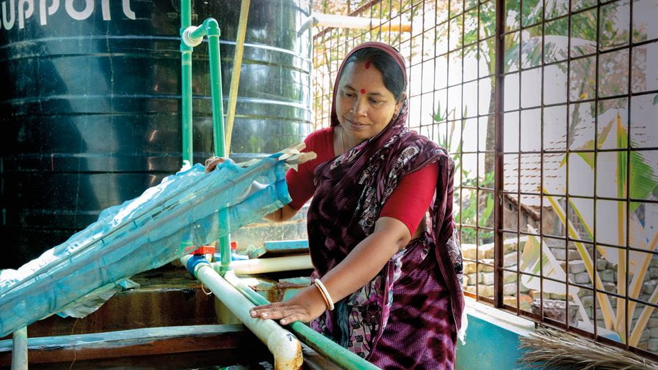 A woman in traditional clothing checks the equipment for a water treatment plant in Bangladesh.