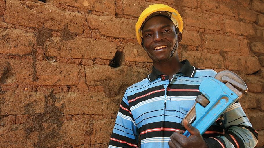 Um encanador da República Democrática do Congo segurando uma ferramenta de encanamento de metal azul