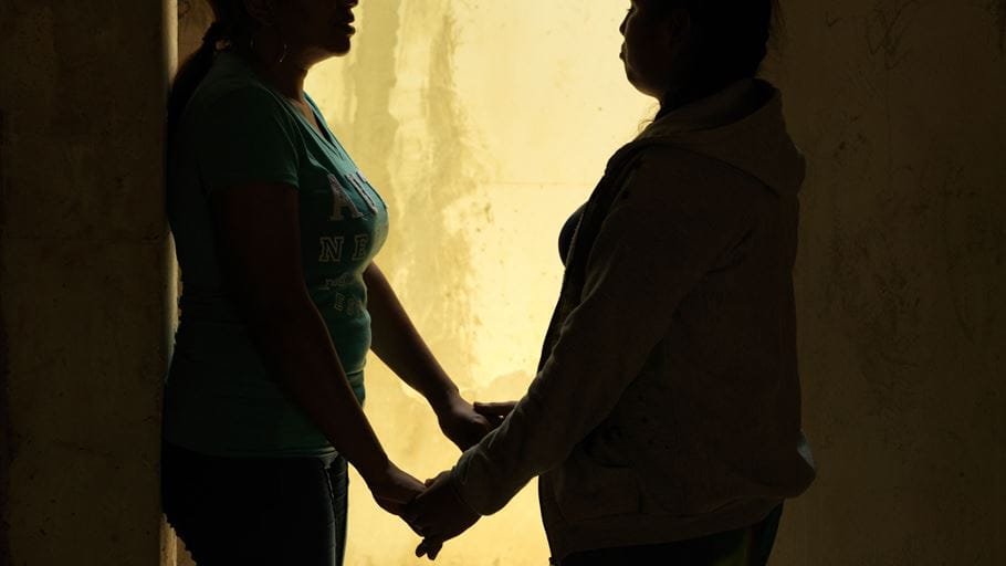 Silhouette of and older and younger woman supportively holding hands