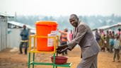 A Congolese man washes his hands at a community wash station