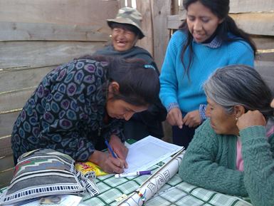 Un groupe de quatre femmes boliviennes, vêtues d’habits chauds, se tiennent autour d’une table, sur laquelle l’une d’entre elles est penchée et remplit un registre.