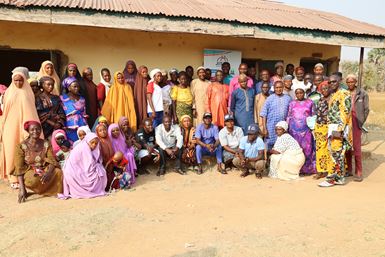 A large number of male and female religious leaders in Nigeria gather for a photograph outside a community building.