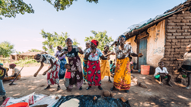 A group of women wearing tradition dresses dance for a crowd in Malawi
