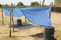 Sistema de captação de água da chuva de custo ultrabaixo no Sudão do Sul, usando uma lona plástica, estacas de madeira e um tambor de combustível de plástico. Foto Murray Burt/Tearfund