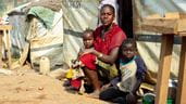 Dheve Chantal et ses trois enfants assis à l'extérieur d'un abri temporaire dans un camp pour personnes déplacées en République démocratique du Congo.