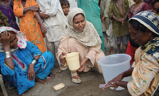 It is important to wash all surfaces of the hands with soap. Rita, a community facilitator (centre), watches over a demonstration of hand washing with soap in a village in UC Jaar, Pakistan. Photo: Richard Hanson/Tearfund