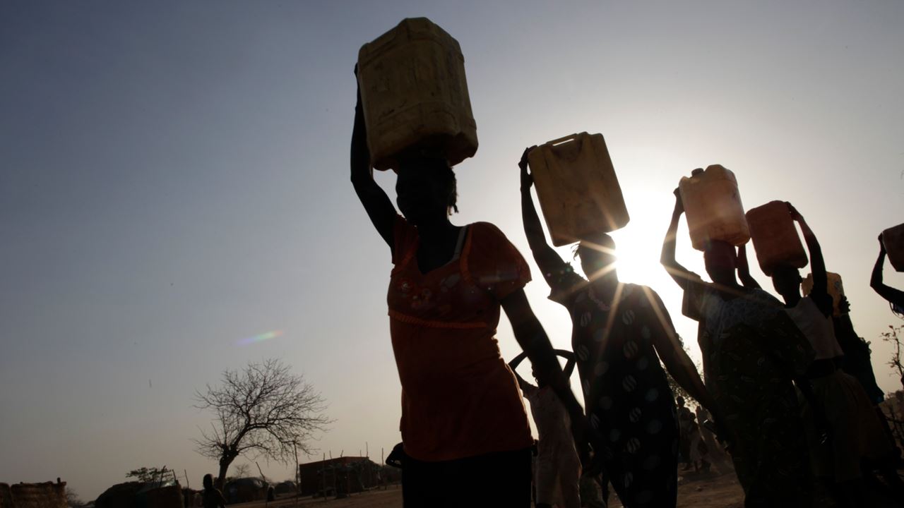 Women from a community in South Sudan return home after collecting water.