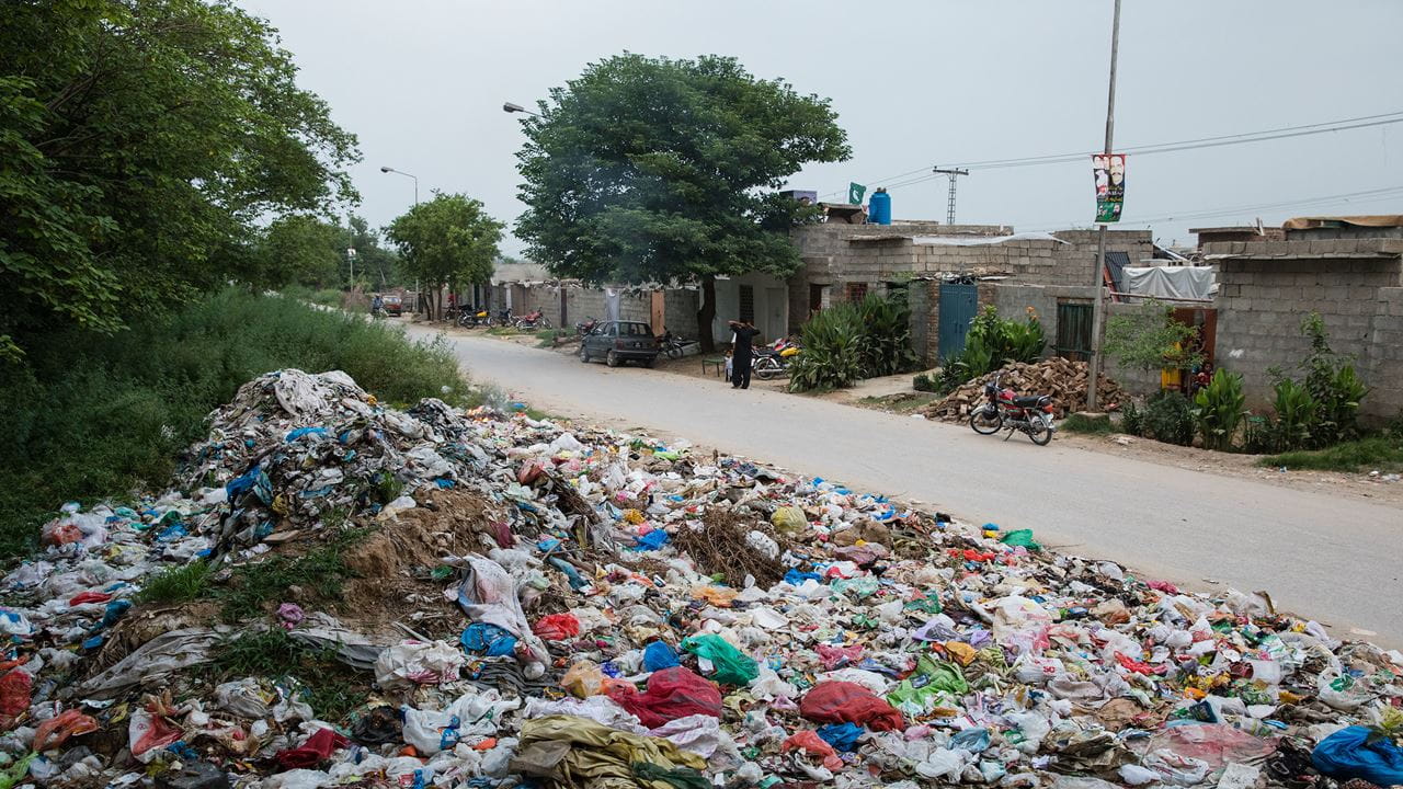 Waste is discarded at the edges of an informal settlement in Islamabad, Pakistan.