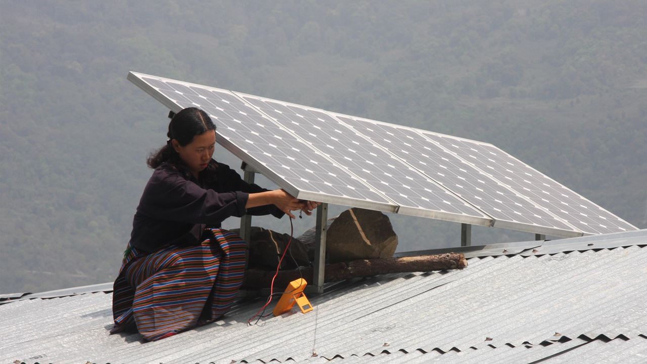 Woman installing solar panels on a roof in Bhutan.
