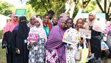 A group of diverse women pose with signs promoting diversity, understanding, and respect.