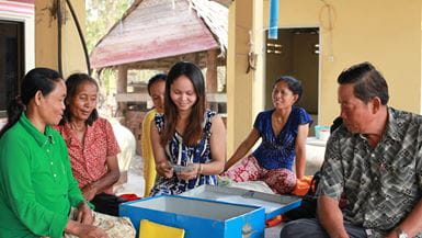 Um grupo de pessoas de um grupo de poupança local no Camboja sentadas juntas e contando seu dinheiro