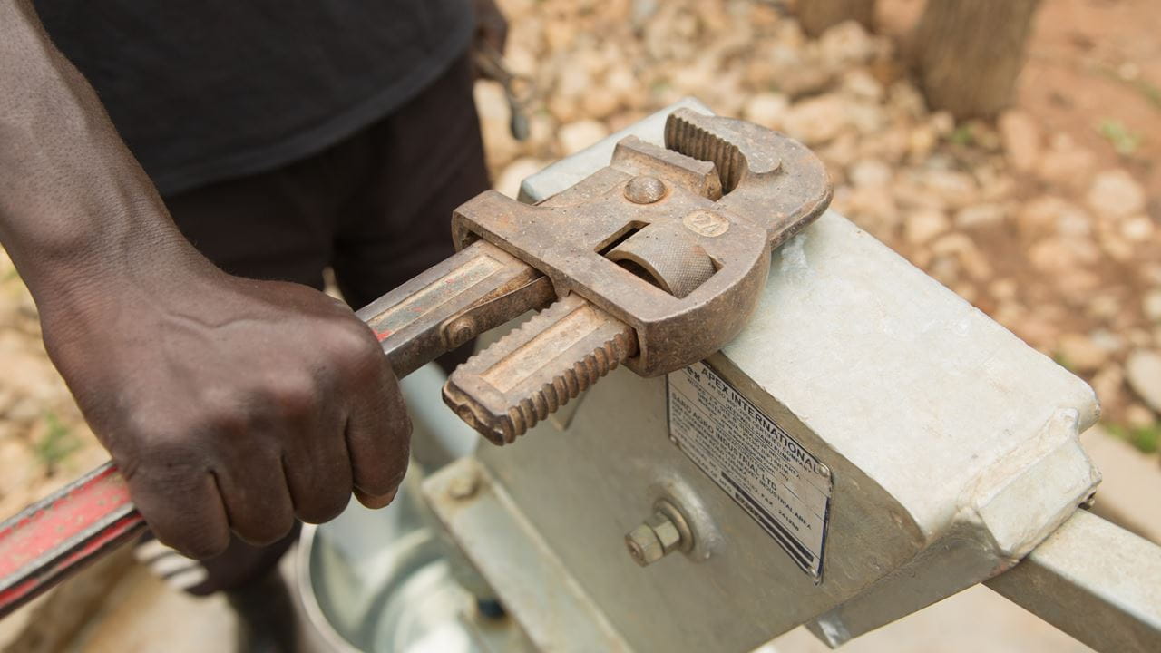 A villager maintains and repairs their water pump