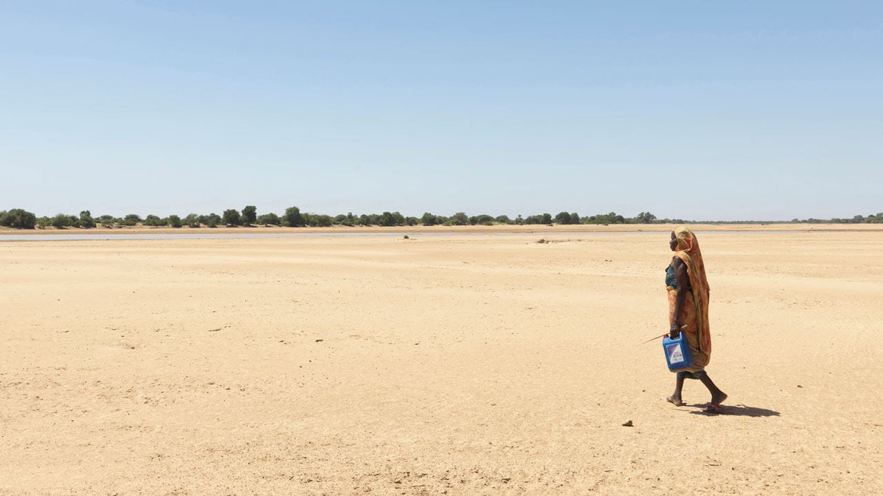 Femme traversant le lit asséché d'une rivière, au Tchad, pour trouver de l'eau. Photo : Peter Caton/Tearfund